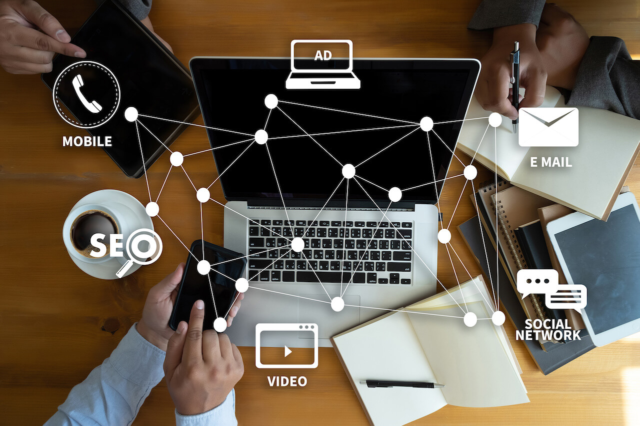Digital marketing channels connected across devices: mobile phone, laptop, and tablet showing SEO, email, video, social