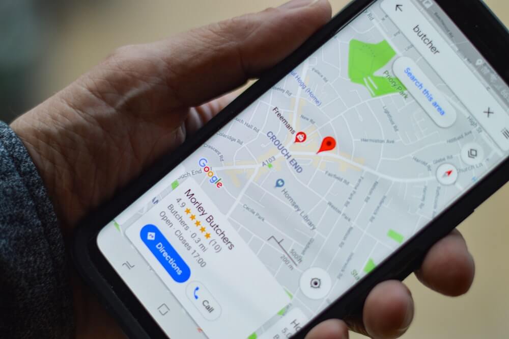 Person holding smartphone displaying Google Maps with local business listings and location pins