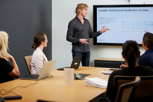 Digital marketing professional presenting paid search data insights to team members in meeting room