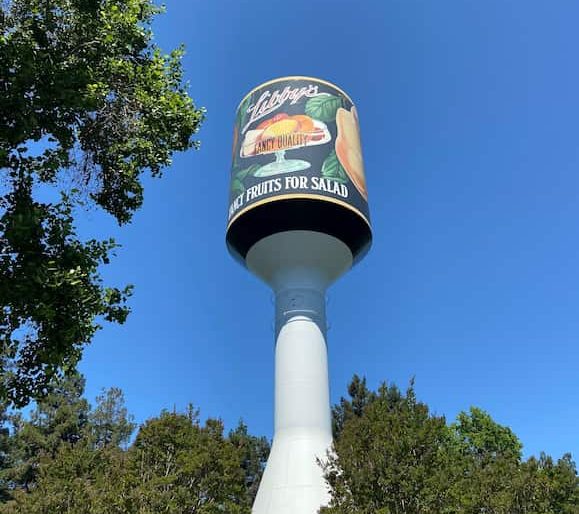 Vintage water tower with Libby's brand sign under blue sky surrounded by trees
