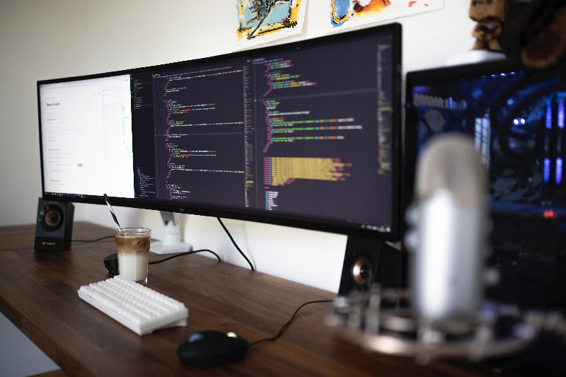 Developer workspace with dual monitors displaying code and analytics dashboards
