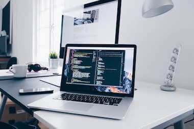 Laptop displaying web development code on a clean desk workspace