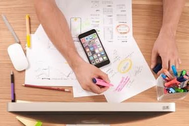 Digital marketer planning social media strategy with sketches and smartphone at desk