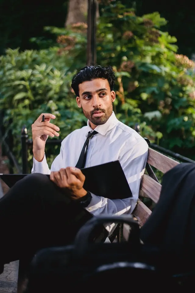 Professional man in white shirt and tie holding tablet, gesturing while discussing digital marketing strategy outdoors