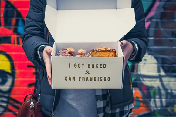 Person holding open bakery box with pastries and "I Got Baked in San Francisco" text