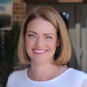 Smiling woman with shoulder-length brown hair wearing a light blue top, professional headshot