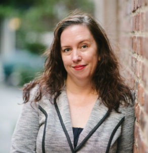 Professional headshot of Erika Heald against a brick wall backdrop