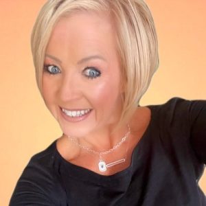 Pam Moore, blonde woman smiling at camera wearing black shirt