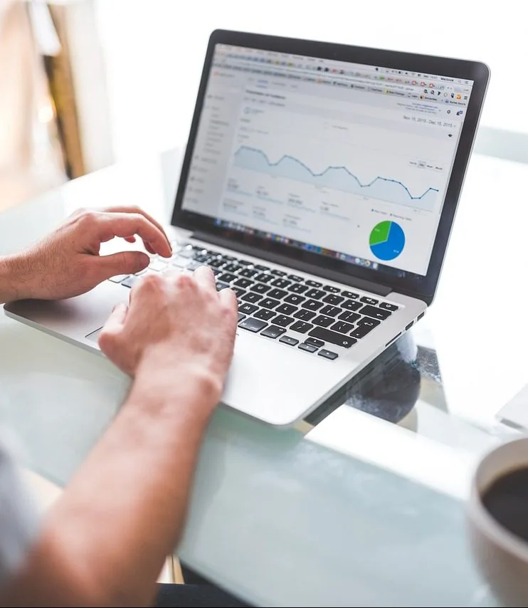 Person reviewing analytics dashboard on laptop with line graph and pie chart data