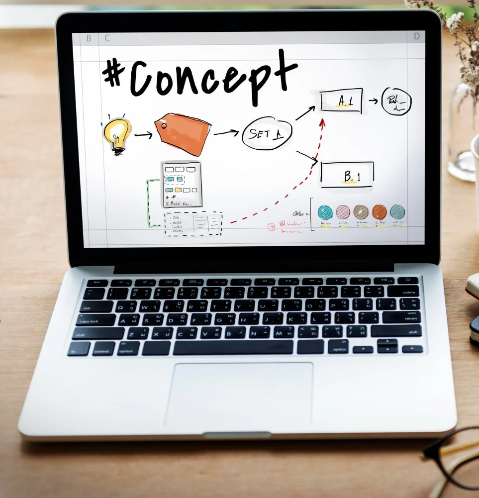 Laptop displaying hand-drawn digital marketing concept diagram with lightbulb, workflow arrows, and color palette