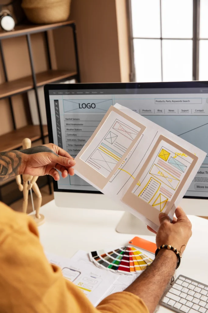 Designer reviewing website wireframe and color palette on desktop workspace