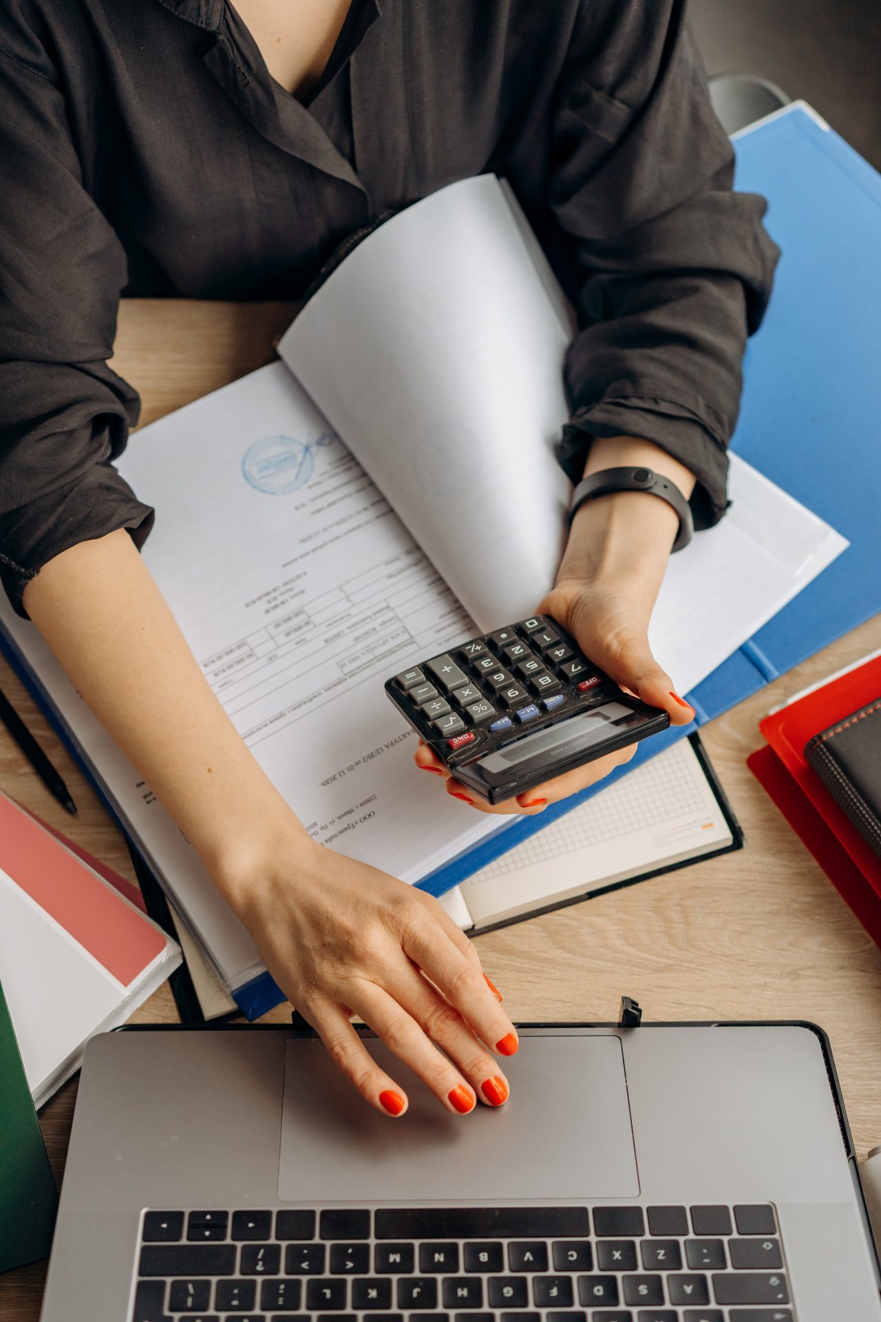 Professional working with financial documents, calculator, and laptop for accounting or business analysis
