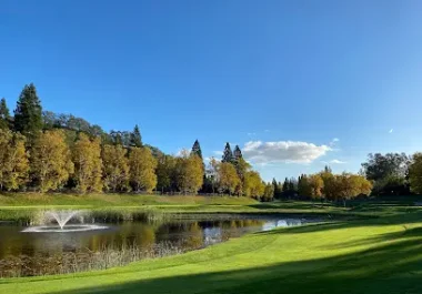 Scenic Blackhawk Country Club landscape with fountain, pond, manicured green grass, and trees under blue sky
