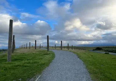 Gravel pathway through Byxbee Park with wooden posts and green fields under blue sky