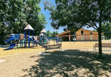 Creekside Park playground with blue play structures and community building in Cupertino