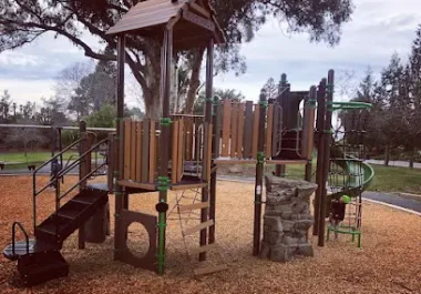 Wooden playground structure with slides and climbing features at East Avenue Park in Hayward