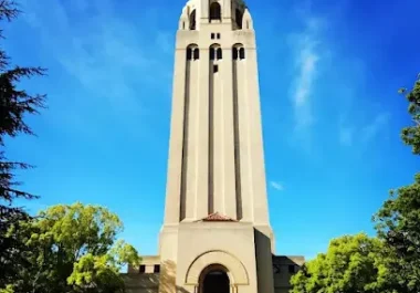 Hoover Tower, a tall cream-colored landmark tower with a golden dome top against a blue sky