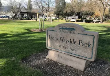Lions Wayside Park entrance sign in Pleasanton, CA with green lawn and trees