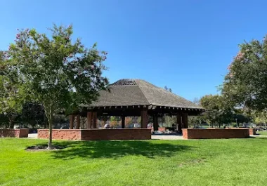 Ortega Park pavilion in Sunnyvale with green lawn and trees under clear sky