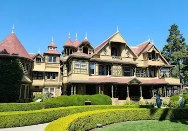 Winchester Mystery House historic Victorian mansion with turrets and manicured gardens under clear blue sky