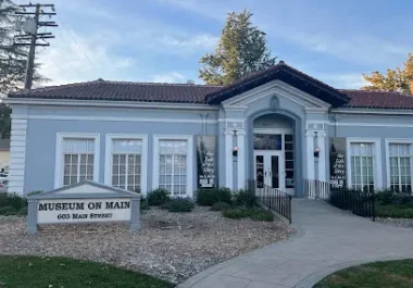 Historic white building with black roof, Museum on Main sign, located in Pleasanton