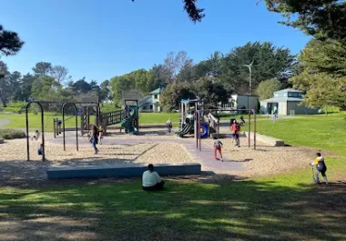 Community park playground with children playing on equipment and climbing structures