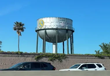 Stockton water tower with palm tree and parked vehicles on street below